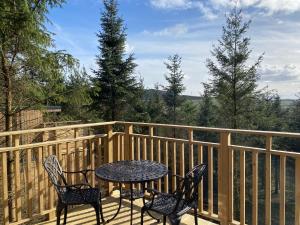 a table and two chairs on a deck with a view at Beechnut Lodge with Hot Tub in Cupar