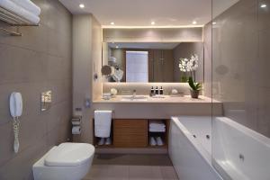 a bathroom with a sink and a toilet and a mirror at Royal Apollonia by Louis Hotels in Limassol