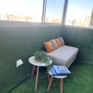 Un sofá y mesas en una habitación con una pared verde. en DPTO LUMINOSO Y CÓMODO ROSARIO, en Rosario 36 fotos más