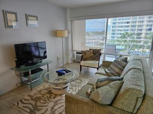 een woonkamer met een bank en een flatscreen-tv bij Ilikai Hotel Condo with Kitchen and Ocean View in Honolulu