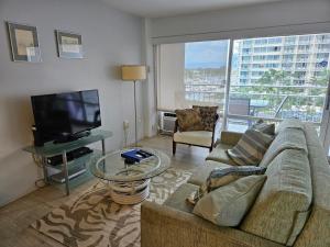 a living room with a couch and a flat screen tv at Ilikai Hotel Condo with Kitchen and Ocean View in Honolulu