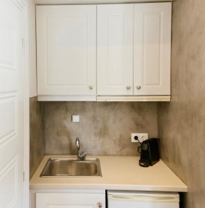 uma cozinha com armários brancos e um lavatório em Ammos Luxury Suite em Caristo