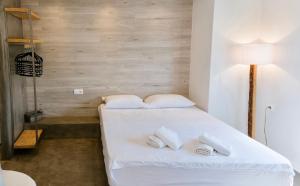 een slaapkamer met een bed met witte lakens en kussens bij Ammos Luxury Suite in Karistos