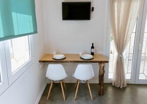 a dining room table with two white chairs and a television at Ammos Luxury Suite in Karistos