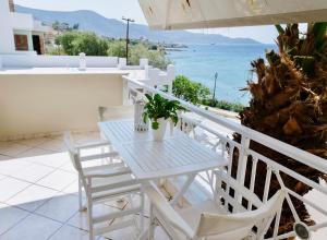 een witte tafel en stoelen op een balkon met uitzicht op de oceaan bij Ammos Luxury Suite in Karistos