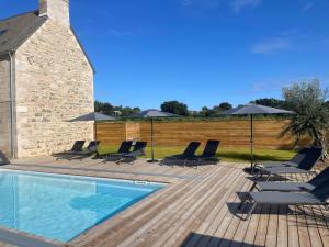 a swimming pool with lounge chairs and umbrellas at Domaine du Mimosa in Perros-Guirec