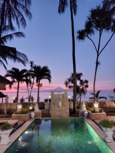 una piscina con vistas al océano por la noche en Puri Mas Boutique Resort & Spa, en Senggigi 