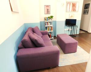 ein lila Sofa und einen Stuhl im Wohnzimmer in der Unterkunft sous les deux tours - SWEET JANE apartment in Bologna
