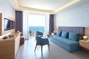 a living room with a blue couch and a table at Royal Apollonia by Louis Hotels in Limassol