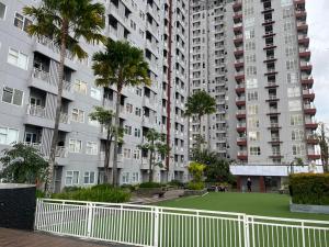a large apartment complex with palm trees and a white fence at VidaView Apart for Family Syariah by NAD in Pampang