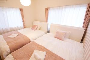 two beds in a small room with windows at Primehome Ninomiya in Fukiaichō