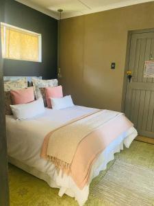 a bedroom with a large bed with pink and white pillows at Doornboom Farm Self Service in Heidelberg