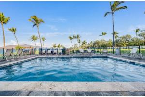 una piscina con sillas y palmeras en Kihei Surfside, #511 condo, en Wailea