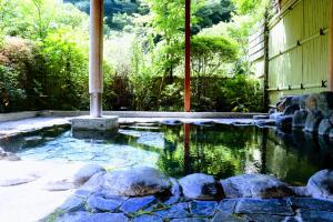 a pool of water with rocks in a garden at Onsen Guest House Tsutaya in Hakone
