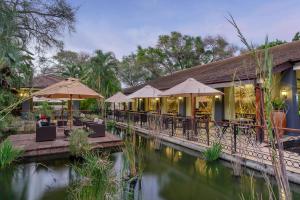 un restaurante con mesas y sombrillas junto a un río en Protea Hotel by Marriott Livingstone, en Livingstone