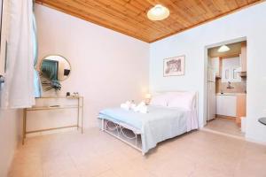 Biała sypialnia z łóżkiem i kuchnią w obiekcie Andromache's w mieście Gastouri