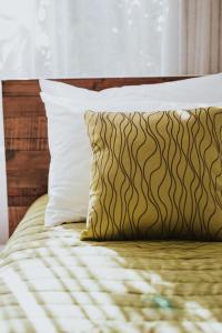 a bed with a brown and white pillow and a window at Peninsula Motel in Whitianga