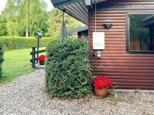 uma casa com um arbusto com flores vermelhas em frente em 8 person holiday home in Svendborg em Svendborg
