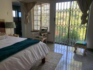 a bedroom with a bed and a large window at Maisha@Toti in Amanzimtoti