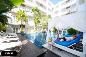 a man and a woman sitting on a swing by the pool at a hotel at Grand Ixora Kuta Resort in Kuta