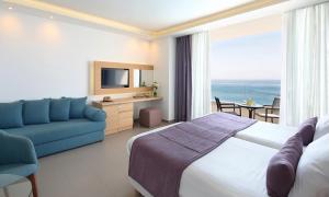 a hotel room with a bed and a blue couch at Royal Apollonia by Louis Hotels in Limassol