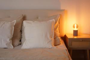 a bed with white pillows and a candle on a night stand at Nordic Living im Zentrum Wismars in Wismar