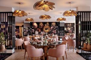 a restaurant with a table and chairs and chandeliers at Royal Apollonia by Louis Hotels in Limassol
