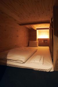 a large bed in a wooden room with a window at Onsen Guest House Tsutaya in Hakone