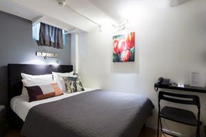 Dormitorio con cama, escritorio y pintura en Quentin England Hotel, en Ámsterdam