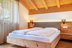 a bed in a bedroom with a wooden ceiling at Villa Solinda App Puccini in Selva di Val Gardena