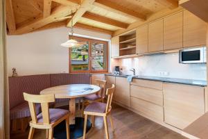 a kitchen with a wooden table and chairs in a room at Villa Solinda App Puccini in Selva di Val Gardena