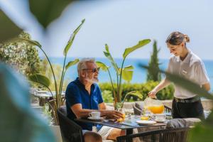 a woman talking to a man sitting at a table at Royal Apollonia by Louis Hotels in Limassol