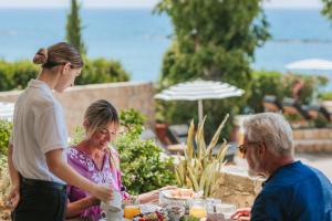 three people sitting at a table with food at Royal Apollonia by Louis Hotels in Limassol