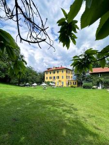 een groot geel gebouw in een grasveld bij Hotel Villa Simplicitas in San Fedele Intelvi