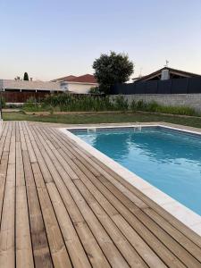 a swimming pool with a wooden deck next to a house at House Prestige in Juvignac