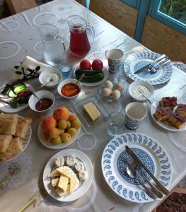 une table blanche avec des assiettes de nourriture dans l'établissement Veli Guest House • საოჯახო სასტუმრო ველი, à Zemo Alvani