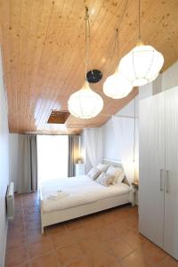 1 dormitorio con 1 cama blanca y 2 lámparas de araña en Hauzify I El Refugi de Prades, en Prades