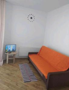 ein Schlafzimmer mit einem orangenen Bett und einem Tisch mit einem TV in der Unterkunft Сихів Новобудова Іскра in Lwiw