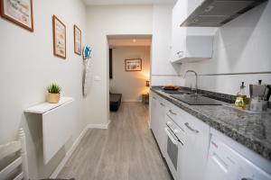 - une cuisine avec des placards blancs et un évier dans l'établissement Apartamentos Doña Concha, à Séville