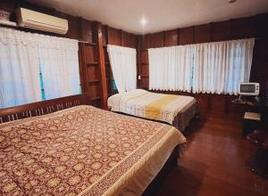 two beds in a hotel room with windows at Baanmai Phaipa House in Sai Yok