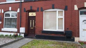 una casa in mattoni rossi con due finestre e una porta di Arise Comfort Home - Dumers Lane, Radcliffe, Bury, Manchester a Radcliffe