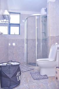 a bathroom with a shower and a toilet and a tub at Chic 2-Bedroom Haven in Kilimani in Nairobi