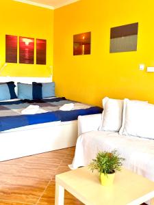Pokój z 2 łóżkami, stołem i żółtą ścianą w obiekcie Balaton BeachSide Apartman Siófok N3 w Siófoku