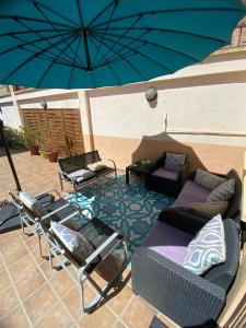 eine Terrasse mit einem Sofa, Stühlen und einem Sonnenschirm in der Unterkunft Casa Rural La Pinta- SendaViva y Bardenas in Villafranca