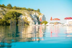 a pool of water with umbrellas and a beach at Divoto Glamping in Balchik