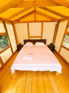 duże łóżko w pokoju z drewnianą podłogą w obiekcie Divoto Glamping w Bałcziku
