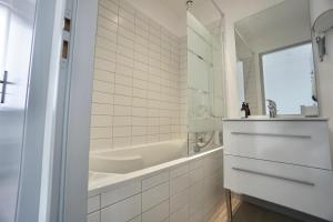 a white bathroom with a tub and a sink at Cabine de plage n°1 *50m de la mer* in Ploemeur +24 photos