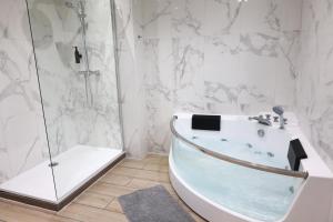 La salle de bains blanche est pourvue d'une baignoire et d'une douche. dans l'établissement Capsule 90's - Jacuzzi - Sauna - Flipper - Billard - Netflix - Nintendo Switch & Jeux -, à Mons