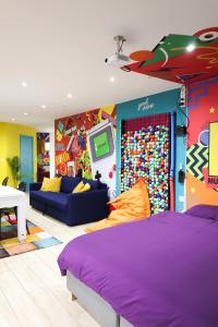 ein Schlafzimmer mit einem lila Bett und einer farbenfrohen Wand in der Unterkunft Capsule 90's - Jacuzzi - Sauna - Flipper - Billard - Netflix - Nintendo Switch & Jeux - in Mons