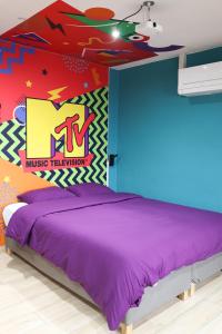 ein Schlafzimmer mit einem lila Bett und einer farbenfrohen Wand in der Unterkunft Capsule 90's - Jacuzzi - Sauna - Flipper - Billard - Netflix - Nintendo Switch & Jeux - in Mons